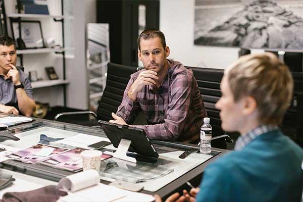 Ryan talking to fellow 特拉维斯马修 coworkers at a conference table